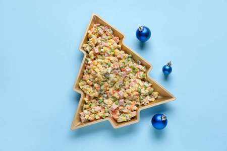 Photo for Plate in shape of Christmas tree with tasty Olivier salad and balls on color background - Royalty Free Image
