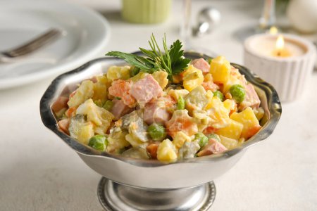 Photo for Metal bowl of tasty Olivier salad on light table, closeup - Royalty Free Image