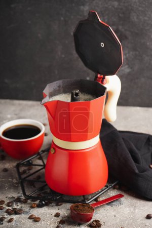 Foto de Cafetera géiser, taza de espresso, frijoles y servilleta sobre la mesa sobre fondo negro grunge - Imagen libre de derechos