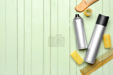 Sprays para el cabello con rizadores y peines sobre fondo de madera verde
