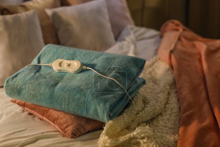 Electric heating pad with pillow on bed at night, closeup