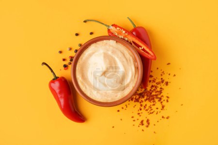 Téléchargez les photos : Bol de sauce chipotle savoureuse et poivrons jalapeno frais sur fond de couleur - en image libre de droit