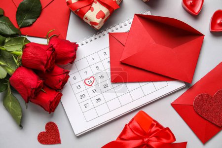 Calendar with marked date of Valentine's Day, envelopes, roses and gifts on grey background