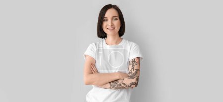 Beautiful smiling tattooed woman on light background
