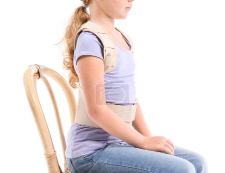 Little girl in back brace sitting on white background
