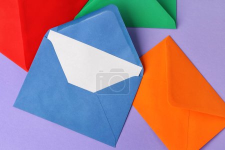 Différentes enveloppes en papier sur fond lilas, gros plan