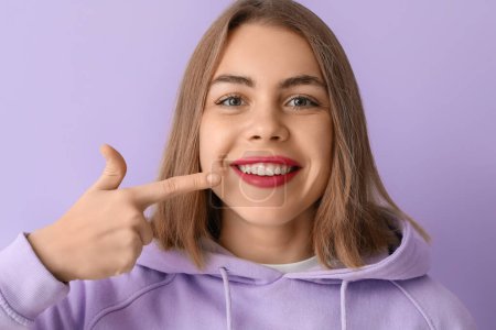 Foto de Mujer joven señalando sus dientes sobre fondo lila, primer plano - Imagen libre de derechos