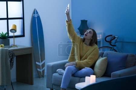 Young woman getting mobile communication at home during blackout