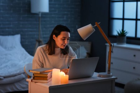 Junge Frau benutzt Laptop bei Stromausfall zu Hause