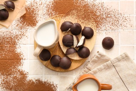 Téléchargez les photos : Planches à découper avec bonbons au lait d'oiseau doux, cruches de lait et pépites de chocolat sur fond de tuiles - en image libre de droit