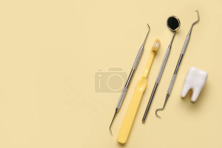 Foto de Herramientas dentales con diente de plástico y cepillo sobre fondo amarillo - Imagen libre de derechos