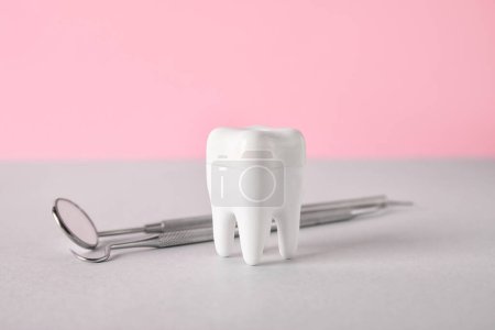 Foto de Diente de plástico con herramientas dentales sobre la mesa sobre fondo rosa - Imagen libre de derechos