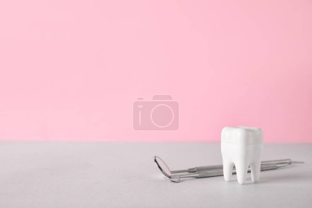 Foto de Diente de plástico con herramientas dentales sobre la mesa sobre fondo rosa - Imagen libre de derechos