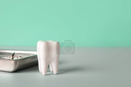 Foto de Diente de plástico con herramientas dentales en la mesa sobre fondo verde, primer plano - Imagen libre de derechos