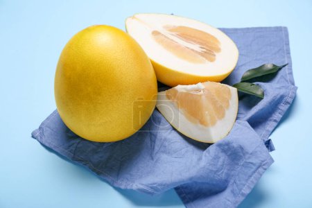 Whole and cut sweet ripe pomelo fruits on blue background, closeup
