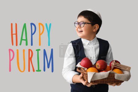 Little Jewish boy with gragger for Purim holiday and fruits in basket on light background