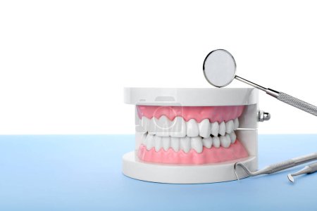 Foto de Modelo de mandíbula con herramientas dentales sobre mesa azul sobre fondo blanco - Imagen libre de derechos