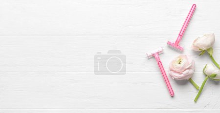 Téléchargez les photos : Safety shaving razors and ranunculus flowers on white wooden background with space for text - en image libre de droit