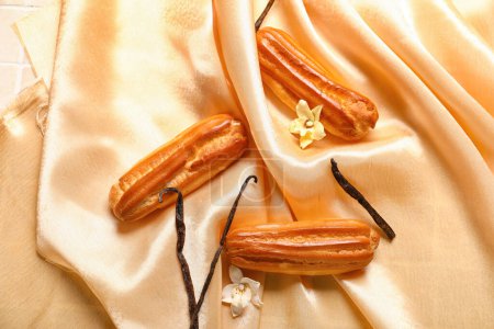 Téléchargez les photos : Sweet eclairs and vanilla sticks on fabric background - en image libre de droit