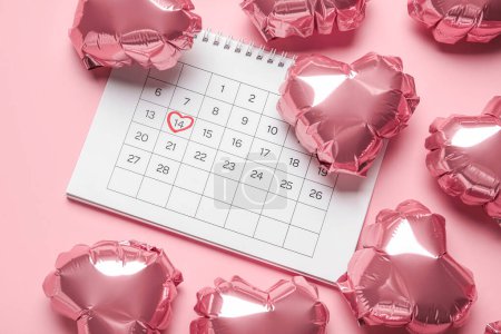 Foto de Calendar with marked date of Valentine's Day and balloons on pink background - Imagen libre de derechos