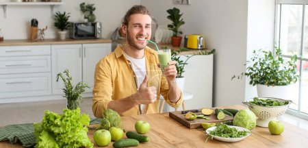 Téléchargez les photos : Jeune homme boire un smoothie vert sain dans la cuisine - en image libre de droit