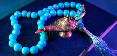Foto de Aladdin lamp of wishes, tasbih and Koran on blue background - Imagen libre de derechos