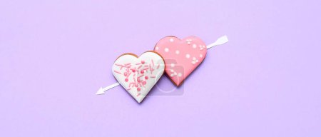 Foto de Composition with tasty heart shaped cookies and paper arrow on lilac background. Valentine's Day celebration - Imagen libre de derechos