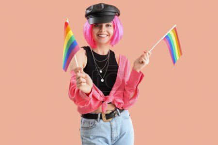 Beautiful young woman with LGBT flags on pink background