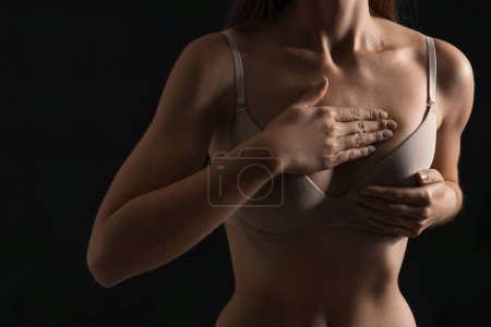 Téléchargez les photos : Young woman in underwear on dark background, closeup. Breast cancer awareness concept - en image libre de droit