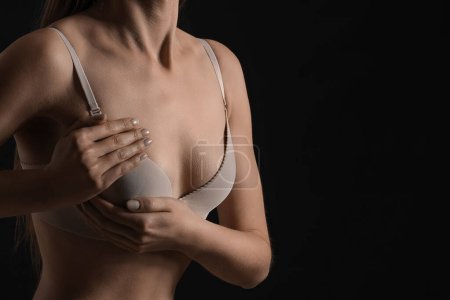 Téléchargez les photos : Young woman in underwear on dark background, closeup. Breast cancer awareness concept - en image libre de droit