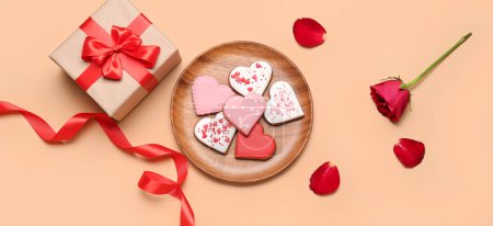 Foto de Composition with tasty heart-shaped cookies, gift and rose on beige background. Valentine's Day celebration - Imagen libre de derechos