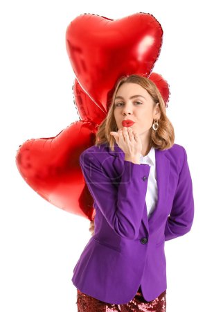 Foto de Beautiful young woman with red heart-shaped balloons blowing kiss against white background - Imagen libre de derechos