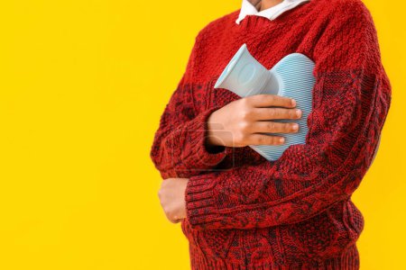 Photo for Ill boy with hot water bottle on yellow background, closeup - Royalty Free Image