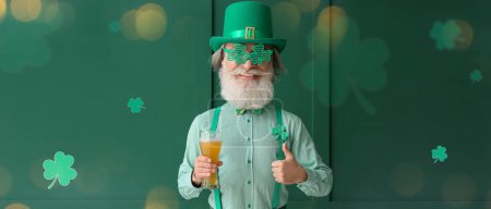 Photo for Happy senior man with big head and glass of beer showing thumb-up gesture on green background. St. Patrick's Day celebration - Royalty Free Image