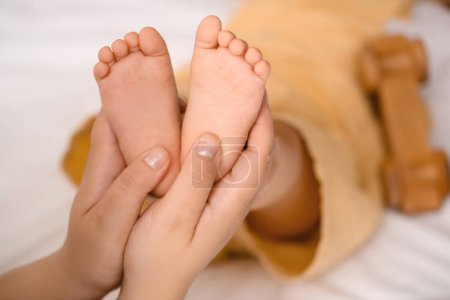 Téléchargez les photos : Mother massaging her baby's feet in bedroom, closeup - en image libre de droit
