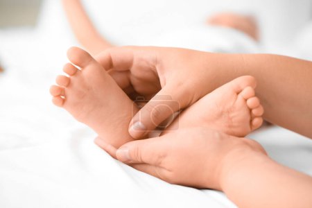 Téléchargez les photos : Mother massaging her baby's feet in bedroom, closeup - en image libre de droit