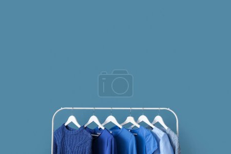 Photo for Rack with blue clothes near color wall - Royalty Free Image