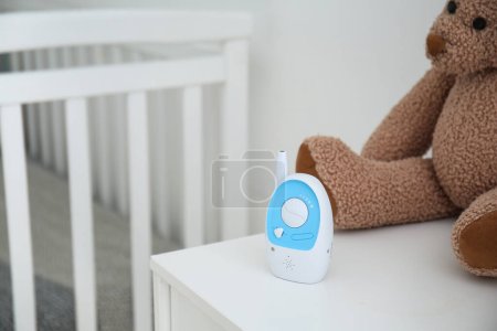 Modern baby monitor with toy on table in room, closeup