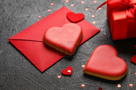 Foto de Composition with sweet cookies, envelope and gift box on dark background, closeup. Valentines Day celebration - Imagen libre de derechos
