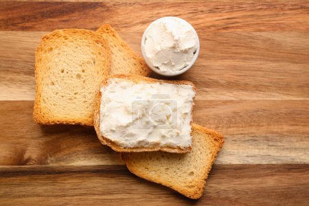 Téléchargez les photos : Toasts with tasty cream cheese on wooden background - en image libre de droit