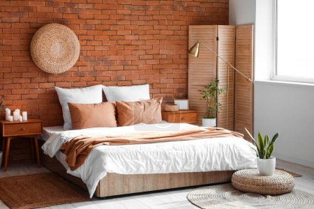 Foto de Interior of modern bedroom with wooden tables, folding screen and houseplants - Imagen libre de derechos