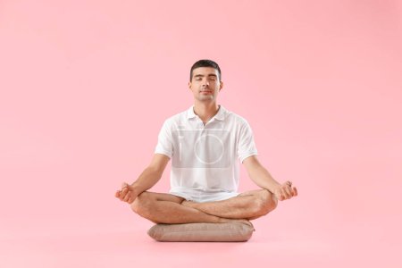 Téléchargez les photos : Young man meditating on pink background - en image libre de droit