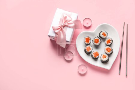 Photo for Plate with sushi rolls, chopsticks, gift and candles on pink background. Valentine's Day celebration - Royalty Free Image