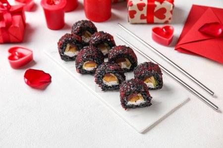 Téléchargez les photos : Board with sushi rolls, chopsticks, candles and gifts on white background, closeup. Valentine's Day celebration - en image libre de droit