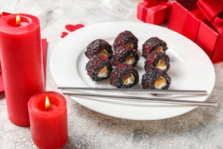 Téléchargez les photos : Plate with sushi rolls, candles and gifts on grunge background, closeup. Valentine's Day celebration - en image libre de droit