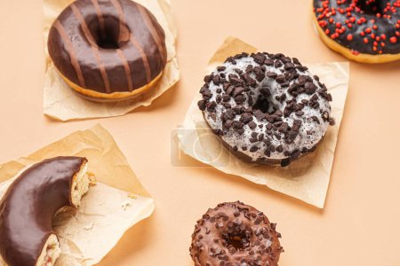 Téléchargez les photos : Parchments with different delicious donuts on beige background - en image libre de droit