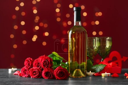 Téléchargez les photos : Bottle of wine, rose flowers and burning candles on black table against blurred lights. Valentine's Day celebration - en image libre de droit