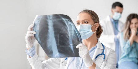 Médico femenino con imagen de rayos X de pulmones en clínica
