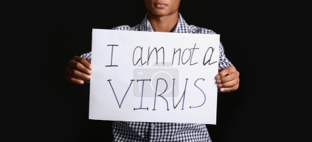 Téléchargez les photos : Adolescent afro-américain avec affiche sur fond sombre. Arrêtez le racisme - en image libre de droit