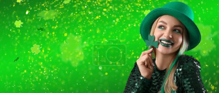Beautiful woman holding clover on green background with space for text. St. Patrick's Day celebration